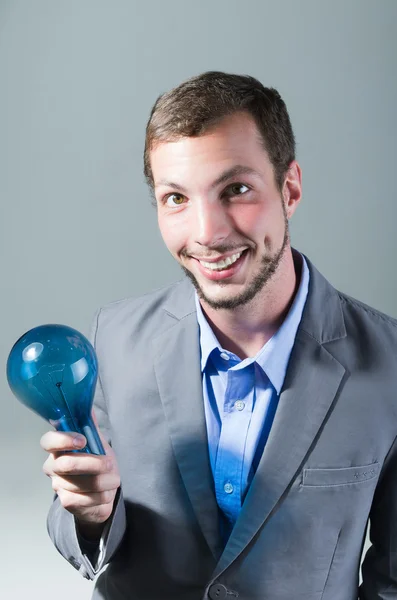 Handsome young smart man holding a blue light bulb — Stock Photo, Image