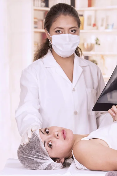 Médico hembra revisando radiografía de una paciente joven —  Fotos de Stock