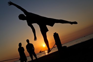 Genç adam Manabi, Ekvator bir plajda slackline Dengeleme silüeti