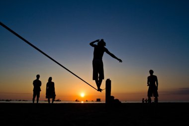 Genç adam Manabi, Ekvator bir plajda slackline Dengeleme silüeti