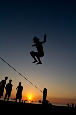 Genç adam Manabi, Ekvator bir plajda slackline Dengeleme silüeti