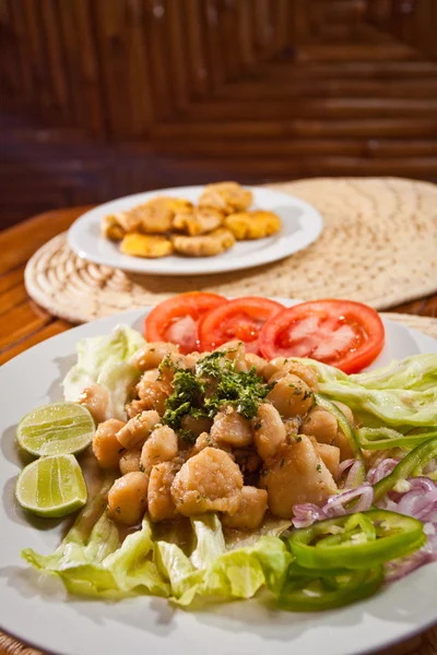 Delicious breaded calamari served with plantain chips — Stock Photo, Image