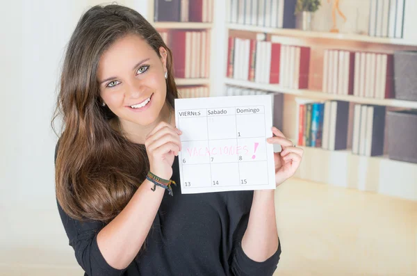 Portrait of pretty brunette girl holding up a calendar — Stock Photo, Image