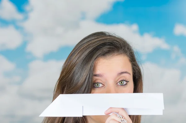 Morena sosteniendo un avión de papel delante de la nube temática de fondo — Foto de Stock