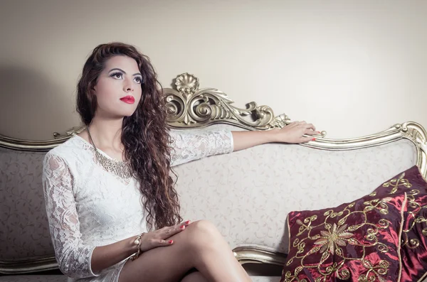 Pretty model girl sitting on victorian sofa posing for camera — Stock Photo, Image