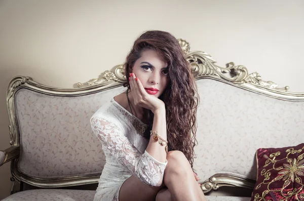 Pretty model girl sitting on victorian sofa posing for camera — Stock Photo, Image