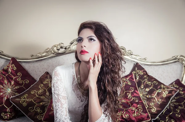 Pretty model girl sitting on victorian sofa posing for camera — Stock Photo, Image