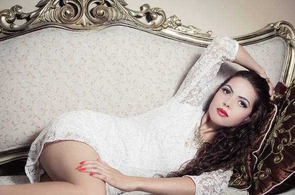 Pretty model girl sitting on victorian sofa posing for camera — Stock Photo, Image