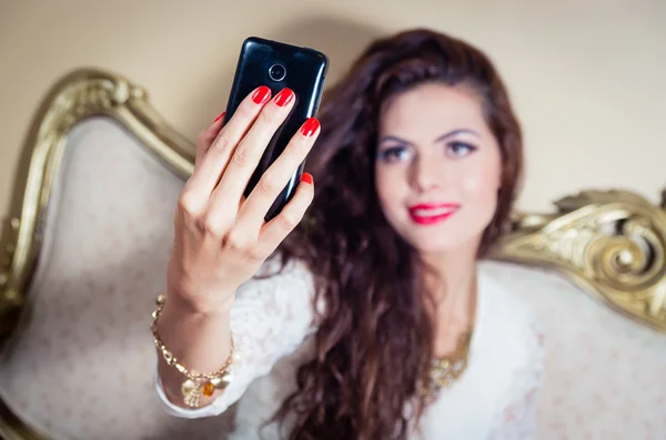 Pretty model girl sitting on victorian sofa posing for camera — Stock Photo, Image