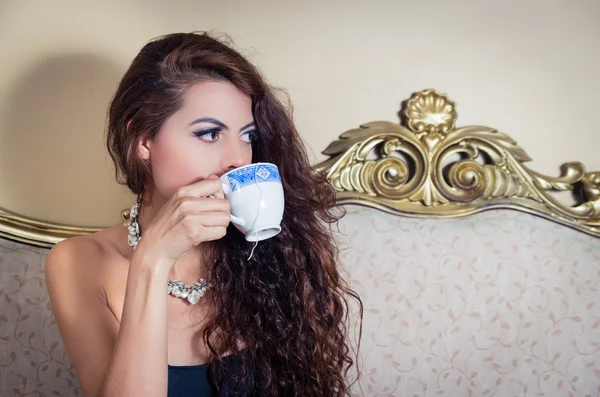 Pretty model girl sitting on victorian sofa posing for camera — Stock Photo, Image