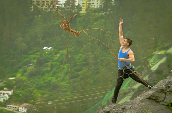 Спортсмен стоїть на скелі кидаючи мотузку вниз по горі — стокове фото