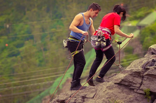 Homem e mulher rapelling montanha abaixo — Fotografia de Stock