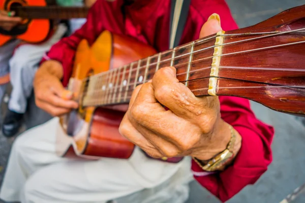 Close up to hands of an indigenous man playing guitar in the central plaza of Armenia, Colombia