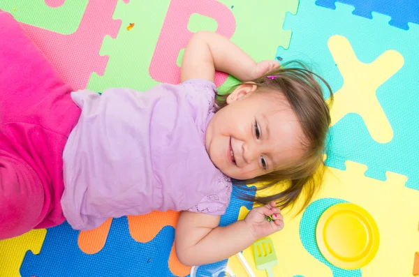 Adorable baby girl lying on floor mats — Stock Photo, Image