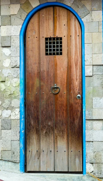 Ancient style rustic wooden door with small metal bar window — Stockfoto