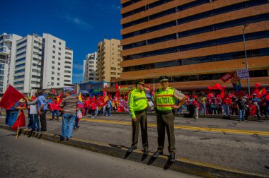 Two ecuadorian policemen wearing uniforms supervising protesters marching in the capital city Quito against government of president Rafael Correa