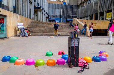 Colorful upturned plastic bowls from street guinea pig gambling and crowd waits to place its bets at carrera 7 one of the main streets in Bogota Colombia