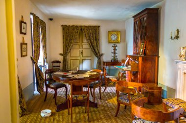 Living room at museum of Simon Bolivar residence in Bogota showing round coffee table with wooden chairs and other interior typical from this time period, Colombia