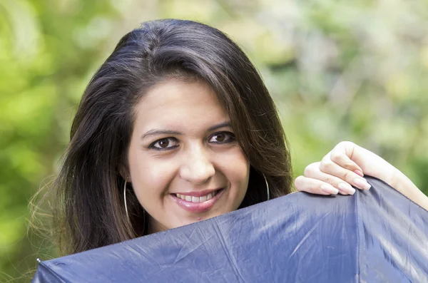Closeup good-looking hispanic brunette woman head peeking up from behind black umbrella smiling to camera with beautiful eyes — Stock Photo, Image