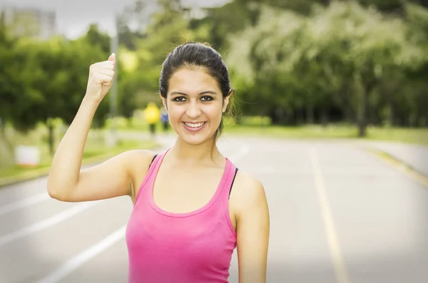 Hispanic brunette in training clothes upper body caption with confident facial expression while holding one arm up — Stockfoto