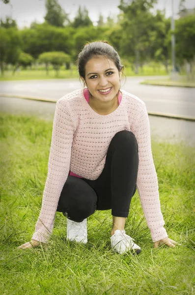 Hispanic brunette model in park with yoga clothes doing starting position pose for camera — Stockfoto