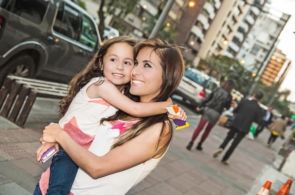 Mamá y su hija en el entorno urbano abrazos — Foto de Stock