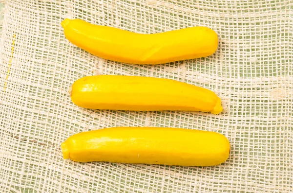 Τρεις φρέσκα βιολογικά κίτρινο κολοκυθάκια σε ύφασμα κάνναβης — Φωτογραφία Αρχείου