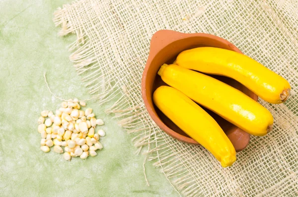 Organic and delicious zucchinis displayed in ceramic terracota bowl with some cut sweet white corn  on hemp a cloth — Stock Photo, Image