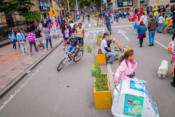 Unidentified hispanic pedestrians, cyclists, dogs and food vendors moving through city street Candelaria area Bogota