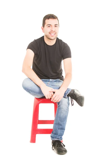Latino joven sentado en taburete rojo —  Fotos de Stock