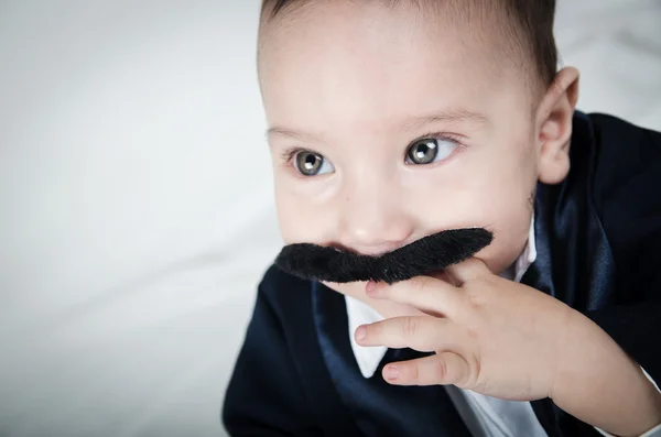 Schattige mooie babyjongen in kostuum met snor en pak — Stockfoto