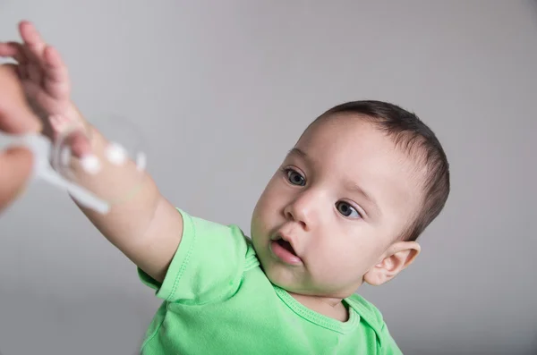 Schattige babyjongen spelen met zeepbel uitrekken arm vooruit geconcentreerd gelaatsuitdrukking — Stockfoto