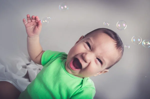 Lindo bebé niño jugando y divertirse con burbujas sonriendo boca abierta mirando a la cámara —  Fotos de Stock