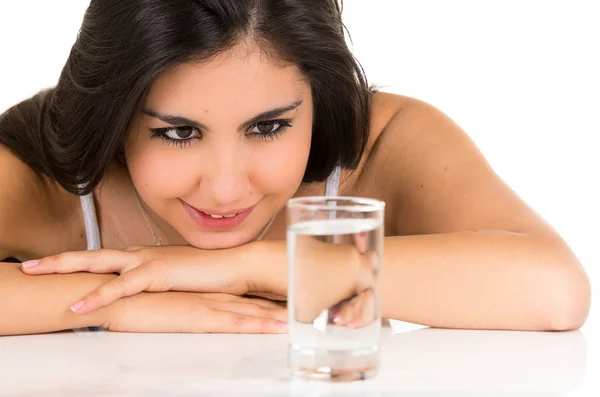 Wunderschöne hispanische junge Mädchen lächelt mit einem Glas Wasser auf ta — Stockfoto