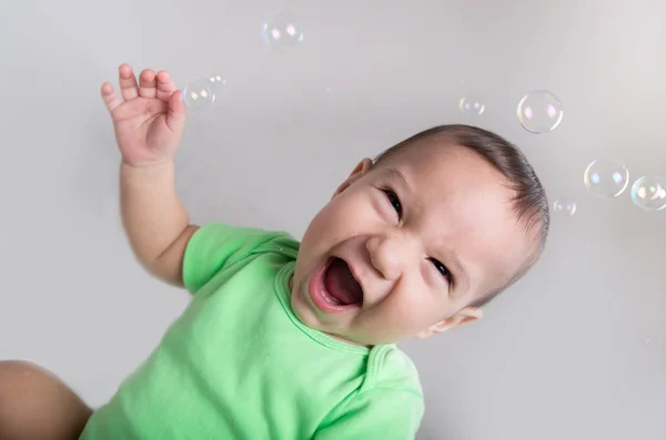 Opgewonden schattige babyjongen in actie spelen met bubbels — Stockfoto