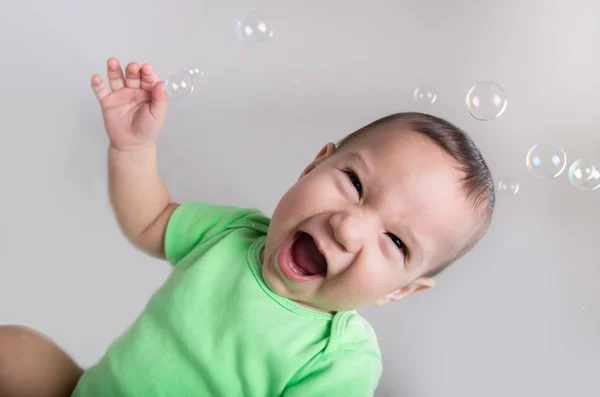 Excited cute baby boy in action playing with bubbles Stock Photo
