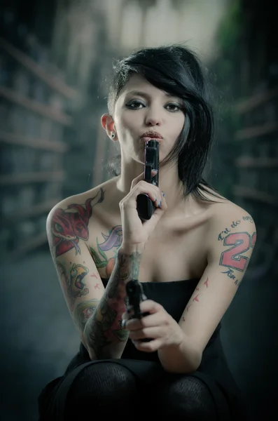 Provocative tattooed girl holding gun — Stock Photo, Image