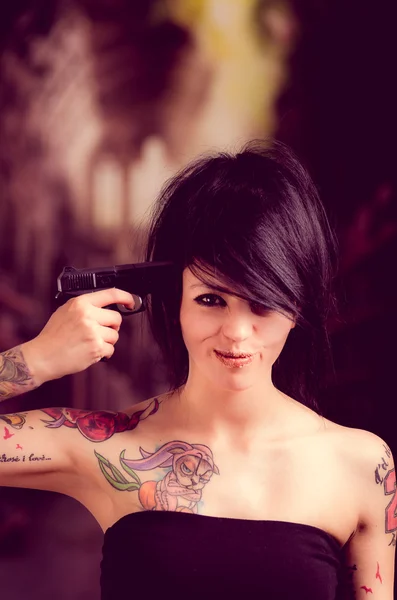 Beautiful tattooed girl with attitude holding gun — Stock Photo, Image