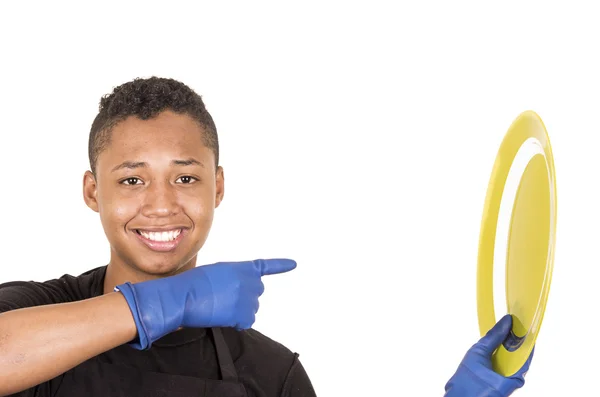 Jovem hispânico vestindo luvas de limpeza azul segurando placa amarela e sorrindo para a câmera — Fotografia de Stock