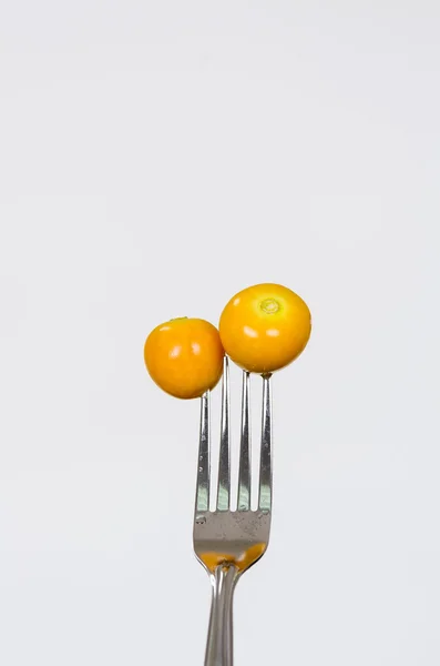 Closeup silver fork with two delicious orange gooseberries and white background — Stock Photo, Image