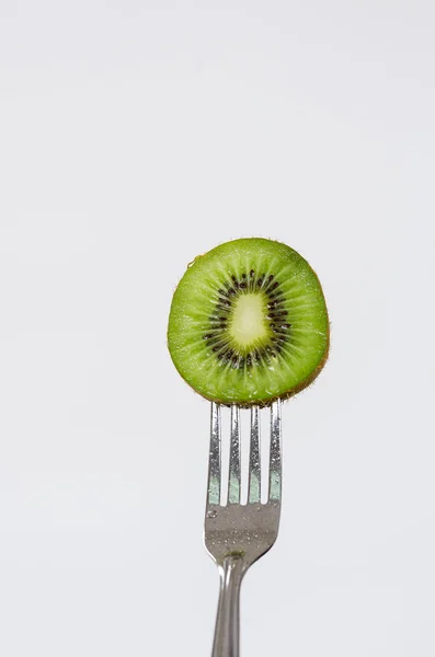 Closeup garfo de prata com peça circular de kiwi verde e fundo branco — Fotografia de Stock