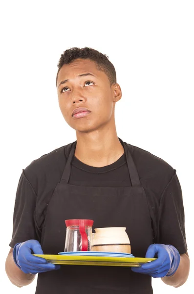 Hispanic young man wearing blue cleaning gloves carrying tray with cups and daydreaming facial expression — Stock Fotó