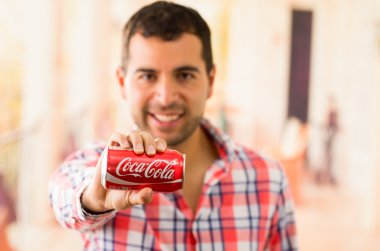 Çekici bir genç adam bir Coca-Cola tutan gülümseyerek olabilir