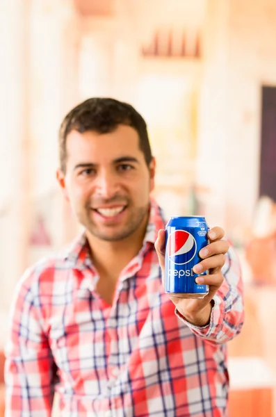 Atractivo joven sonriendo sosteniendo una lata de Pepsi Cola — Foto de Stock