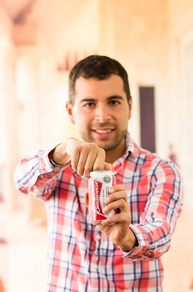 Jovem atraente sorrindo abrindo uma lata de Coca-Cola — Fotografia de Stock