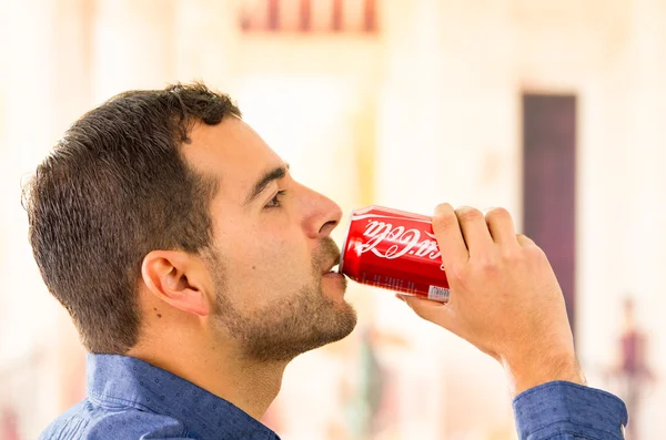 Jeune homme attrayant buvant une boîte de Coca-Cola — Photo