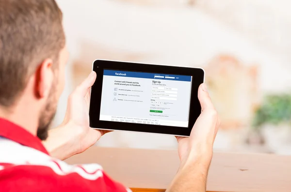 Hombre joven usando tableta mirando el sitio web de Facebook —  Fotos de Stock