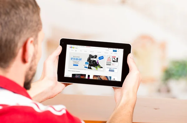 Young man using tablet computer looking at Ebay website — Stock Photo, Image