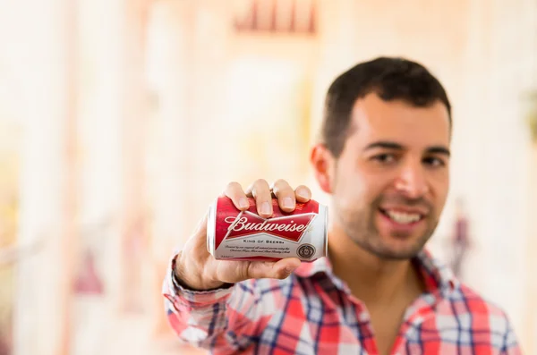 Atractivo joven sonriente sosteniendo una lata Budweiser — Foto de Stock