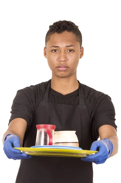 Jeune homme hispanique portant des gants de nettoyage bleus portant un plateau avec des tasses et une expression faciale sérieuse — Photo